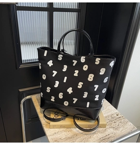 Détail du grand sac cabas en toile noire avec motifs chiffres et anses en cuir brillant