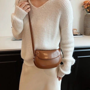 Sac besace marron chic porté par un mannequin en cuir mat avec boucles argentées