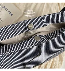 Dettaglio della borsa in tela a righe blu con chiusura magnetica e fodera a spina di pesce