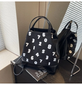 Détail du grand sac cabas en toile noire avec imprimés chiffres et empiècement en cuir poli
