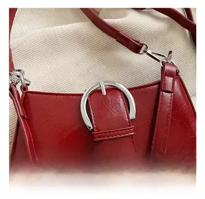 Detailed close-up of the red patent leather texture and silver buckle on the bag