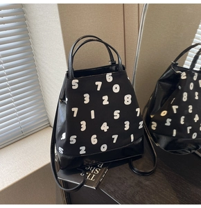 Détail du sac cabas en cuir et toile noirs avec imprimé chiffres blancs et poignée