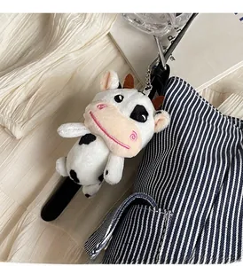 Dettaglio di un simpatico ciondolo a mucca in peluche morbido con cinturino in pelle