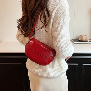 Détail du sac selle rouge en demi-lune avec fini brillant et rivets métalliques