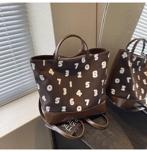 Détail du sac fourre-tout marron foncé avec chiffres blancs, base en cuir et bandoulière