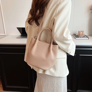 Dettaglio della borsa a secchiello plissettata beige con manico rotondo e parti metalliche