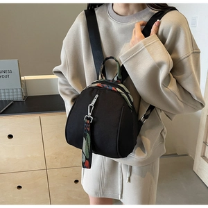 Détail d'un mini sac à dos noir pour femme avec bretelles colorées porté par un modèle