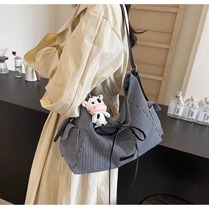 Dettaglio della borsa tote in tela a righe blu con fiocco nero e ciondolo di peluche