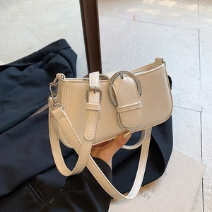 Detail of off-white baguette bag with glossy leather and shiny silver buckle feature