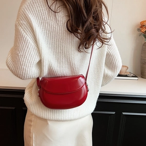 Mannequin portant un sac besace rouge semi-circulaire en cuir verni lisse brillant