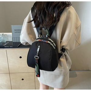 Gros plan du sac à dos en nylon noir avec sangle jacquard colorée et fermetures éclair