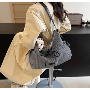 Dettaglio della borsa tote in tela a righe con fiocco nero e portachiavi a mucca