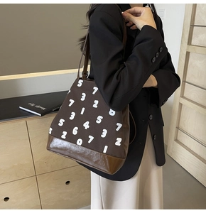 Détail du grand sac cabas en toile marron avec motifs chiffres et base en cuir