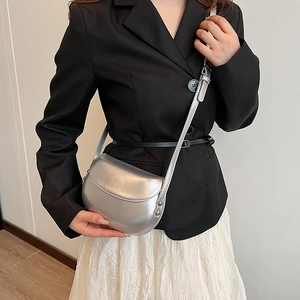 Sacoche selle argentée portée par un mannequin en blazer noir et jupe blanche chic