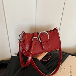 Detailed shot of red leather underarm bag featuring silver buckle and adjustable strap