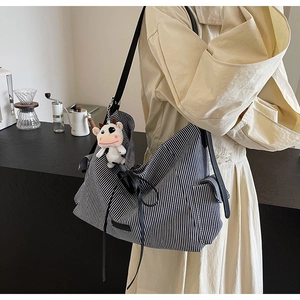 Dettaglio della borsa tote in tela a righe con tracolla, tasca e ciondolo peluche