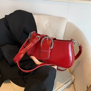 Detail view of vintage red underarm bag featuring a large silver buckle and glossy finish