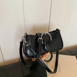 Close-up of black glossy patent leather shoulder bag with vintage silver ring buckle