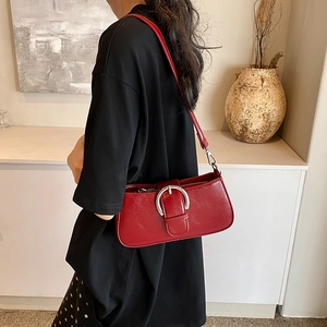 Detail of red baguette bag with silver horseshoe buckle shown on model's shoulder