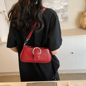 Close-up of vibrant red leather underarm bag featuring a large silver horseshoe buckle