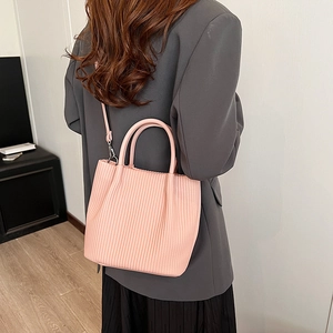 Borsa tote plissettata rosa con tracolla rimovibile indossata su un abito moderno