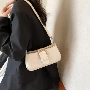 Chic cream leather underarm bag featuring a large silver metal buckle on black blazer