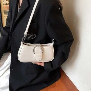 Detail of off-white leather underarm bag with large silver ring buckle on a stylish model