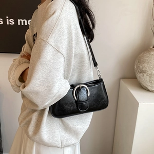 Close-up of black PU leather shoulder bag featuring a large silver metal buckle and soft texture