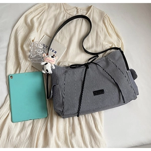 Dettaglio borsa tote in tela a righe con fiocco e simpatico portachiavi a forma di mucca