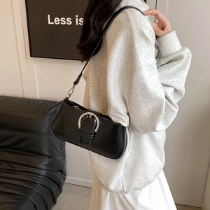 Detail of black leather underarm bag with silver horseshoe buckle on shoulder strap
