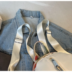 Détail d'un sac à dos blanc avec des rayures multicolores et boucle métallique