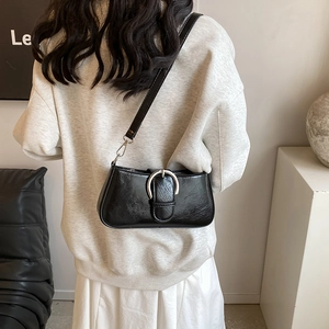 Detail of black faux leather shoulder bag with vintage texture and silver buckle