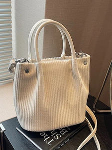 Borsa a secchiello bianca con trama verticale e manici tondi su un libro d'arte