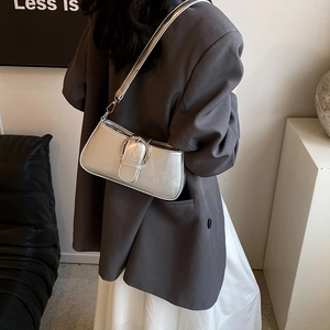 Close-up of silver baguette bag with metallic pleated texture and large round metal buckle