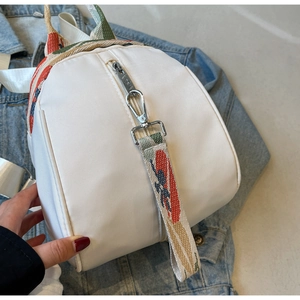 Détail d'un sac à dos blanc en nylon avec bretelles jacquard colorées et ferrures argent