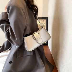 Detailed view of silver baguette bag with metallic texture and buckle on a shoulder strap