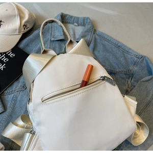 Détail du sac à dos blanc cassé avec oreilles de chat et sangles en nylon brillant