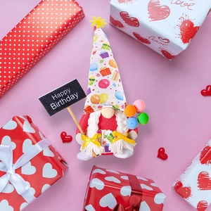 Birthday gnome plush with party hat holding Happy Birthday sign surrounded by gift boxes