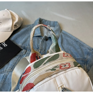 Détail de la poignée en jacquard coloré et fermeture éclair argentée sur sac blanc