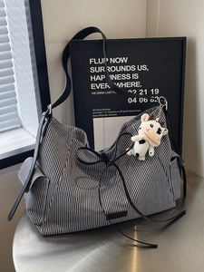 Borsa tote in tela a righe bianche e nere con tracolla in pelle e ciondolo a forma di mucca