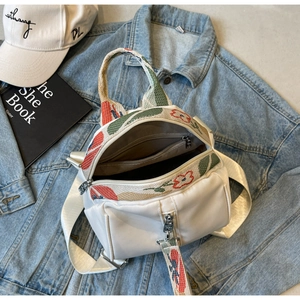 Détail de l'intérieur du mini sac à dos blanc avec poche zippée sur veste en jean