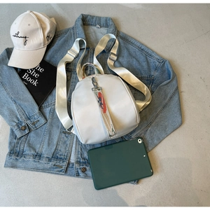 Détail du sac à dos en nylon crème avec sangle imprimée et boucle de réglage en métal argenté