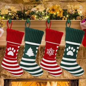 Detail van vier gebreide kerstsokken met pootafdrukken bij een gezellige open haard