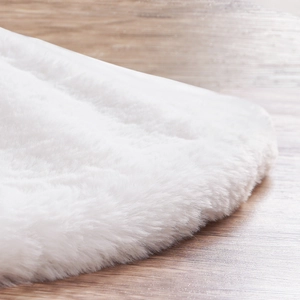 Close-up van de zachte witte pluche kerstboomschort op een warme houten ondergrond