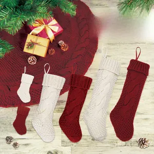 Detailansicht der grob gestrickten Weihnachtssocken und Baumdecke in rustikalem Rot und Creme