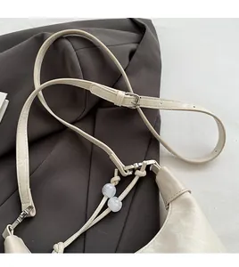 Detailansicht der cremeweißen Tasche mit verstellbarem Riemen und Kugelverzierung