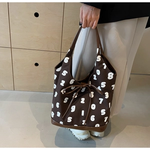 Close-up of canvas bucket bag with leather handles and large numeric print design