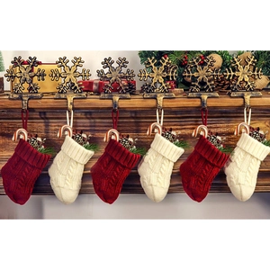 Gestrickte rote und weiße Weihnachtssocken mit Schneeflockenhaltern am Holzkamin