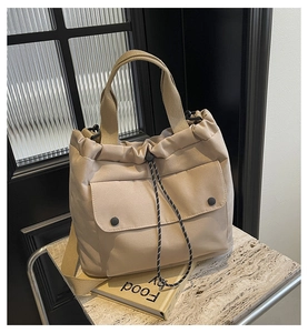 Détail du sac cabas en toile beige montrant le cordon de serrage et la poche à pression