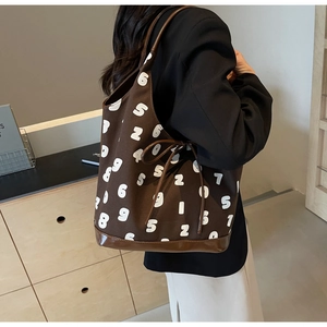 Detail of dark brown canvas tote bag featuring white number prints and drawstring bow detail